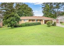 Charming single-story home featuring a well-manicured lawn and attached garage at 3563 Carriage Way, East Point, GA 30344
