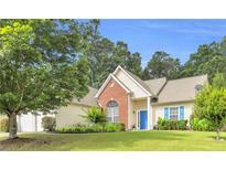 Charming single-Gathering home with a well-manicured lawn, blue door, and a mix of brick and vinyl siding at 1530 Brisbane Dr, Dacula, GA 30019