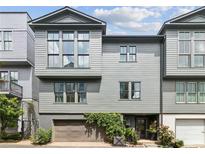 Contemporary townhome with gray siding, large windows, and a two-car garage with verdant foliage at , Atlanta, GA 30315