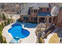 Backyard view with a sparkling pool and hot tub surrounded by a stone patio, perfect for outdoor entertainment at 297 Collegiate Dr, Powder Springs, GA 30127