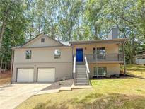 Charming home featuring a two-car garage, light beige siding and a welcoming blue front door at 90 Lake Avalon Ct, Dallas, GA 30157