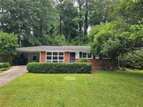 Charming brick home featuring a well-manicured front lawn and mature trees, providing a peaceful setting at 813 Crockett Ct, Decatur, GA 30033
