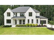 Elegant two-story home with white brick, black trim, manicured lawn and a two-car garage at 6175 River Shore Pkwy, Atlanta, GA 30328