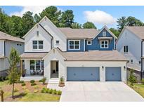 Charming two-story home featuring a three-car garage, white brick, and manicured landscaping at 461 Maypop Ln, Woodstock, GA 30188