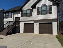 Charming home featuring a two-car garage, a well-maintained lawn, and stairs leading to the front door at 955 Loch Forest Way, Riverdale, GA 30296