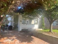 Charming single Gathering home with white brick and green siding, showcasing a covered porch with trees at 3101 E Point St, Atlanta, GA 30344