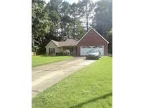 Charming single-story home with a brick facade and well-maintained front yard and a two car garage at 7133 Babbling Brook Dr, Jonesboro, GA 30236