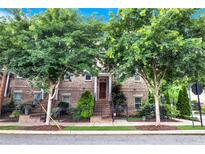 Brick townhouse with meticulously maintained landscaping, sidewalk, and mature trees at 326 Brownstones Ne Cir, Atlanta, GA 30312