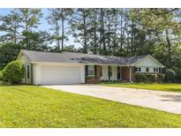 Charming single-story home with a well-manicured lawn, attached two car garage, and mature trees at 4149 Indian Lake Cir, Stone Mountain, GA 30083