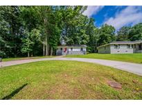Charming single-story home with a well-maintained lawn and a circular driveway, surrounded by lush trees at 10150 Puckett St, Covington, GA 30014