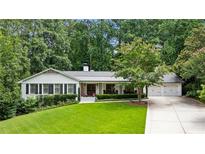 Charming home with a well-manicured lawn, mature trees, and a welcoming facade, complete with a three car garage at 6175 Weatherly Dr, Sandy Springs, GA 30328