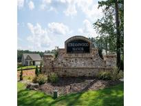 Stone community entrance sign for Streamwood Manor, featuring manicured landscaping and a glimpse of new homes at 15 Regal Ln, Covington, GA 30016