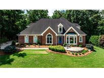 Charming brick home featuring a lush green lawn and mature trees at 215 Settindown Ct, Roswell, GA 30075