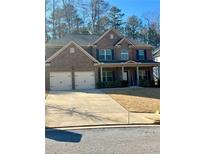 Charming two-story brick home featuring an attached two-car garage and manicured lawn on a sunny day at 2208 Ginger Lake Ne Dr, Conyers, GA 30013
