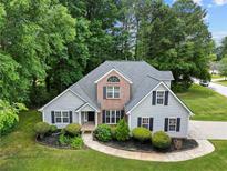 Charming two-story home featuring gray siding, brick accents, a landscaped yard, and mature trees at 504 Bradford Park Ct, Loganville, GA 30052