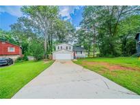 Charming two-story home featuring a well-manicured lawn and an attached garage and lovely landscaping at 446 Jaywood Dr, Stone Mountain, GA 30083