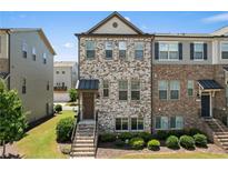 Charming townhome featuring a mix of brick and stone, a covered porch, and professional landscaping at 4458 Dunblane Ave, Sugar Hill, GA 30518