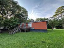 Exterior view of home with green lawn, wooden deck, and mature trees at 25 Dogwood Dr Nw, Cartersville, GA 30121