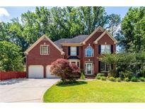 Traditional brick home showcasing an attached two-car garage and meticulously maintained front yard at 5287 Wild Indigo Way, Acworth, GA 30102