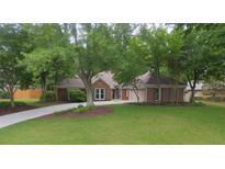 Charming brick home with a lush green lawn, mature trees, and a long driveway leading to a two-car garage at 11940 Wexford Club Dr, Roswell, GA 30075