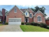 Charming two-story brick home featuring a two-car garage and well-manicured lawn and shrubbery at 1255 Home Place Dr, Lawrenceville, GA 30043