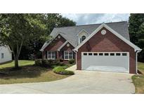 Charming brick home featuring a two-car garage, well-manicured lawn and mature trees at 3066 Gem Creek Rd, Buford, GA 30519