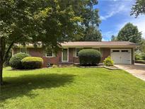 Charming brick ranch with a well-manicured lawn, mature trees, and an attached one car garage at 4212 Worth Nw St, Acworth, GA 30101