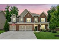 Charming two-story brick home with a three-car garage and well-manicured lawn at twilight at 4972 Park Vale Dr, Sugar Hill, GA 30518
