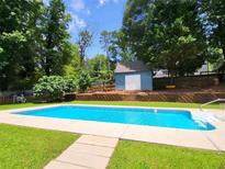 Refreshing backyard pool with a charming blue storage shed and lush landscaping creating a private oasis at 2913 Jordan Forest Trl, Lawrenceville, GA 30044