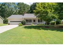 Charming single-story home featuring an attached garage, manicured lawn, and inviting front porch at 334 Bridgewood Se Dr, Conyers, GA 30094