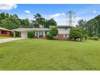 Charming home featuring a well-maintained lawn, a brick facade, and a convenient carport at 5440 Huron Dr, Lake City, GA 30260