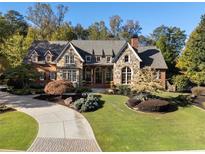 Beautiful stone and brick home with manicured lawn, curved driveway, and mature trees at 4634 Whitestone Way, Suwanee, GA 30024