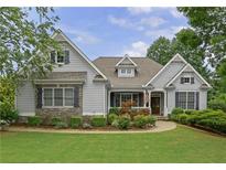 Charming home featuring a manicured lawn, complemented by lush landscaping, stone accents, and classic architectural details at 130 Holly Reserve Pkwy, Canton, GA 30114