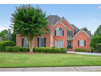 Beautiful brick home featuring a well-manicured lawn, mature tree, and classic architectural details at 1232 Everton Pl, Cumming, GA 30041