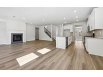 Open-concept living room and kitchen featuring a fireplace, stainless steel appliances, and hardwood floors at 1911 Fairchild Ave, Grayson, GA 30017