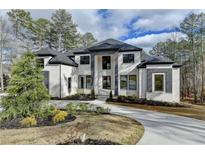 Elegant two-story home with a circular driveway, sophisticated color scheme and beautifully landscaped front yard at 4090 Sandy Lake Dr, Lithonia, GA 30038