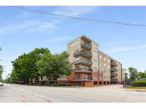 Tan and brick condominium building with balconies and mature trees under a blue sky at 384 Ralph Mcgill Ne Blvd # 123, Atlanta, GA 30312