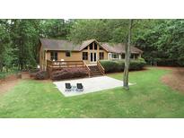 Expansive backyard with mature trees, deck, and stone patio seating area, perfect for outdoor entertaining at 3852 Vinyard Ne Ct, Marietta, GA 30062