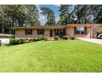 Charming brick ranch with a well-maintained front lawn, shrubs, and a paved driveway at 1472 High Meadow Dr, Stone Mountain, GA 30083