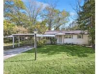 Charming one-story home featuring a carport and a well-maintained lawn at 1703 Barrett Nw Dr, Atlanta, GA 30318