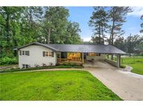 Charming ranch home showcasing a well-manicured lawn, carport, and inviting covered front porch at 2432 Kelly Lake Dr, Decatur, GA 30032