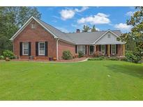 Charming brick home featuring a lush front lawn, mature trees, and inviting front porch at 3992 Spot Rd, Cumming, GA 30040