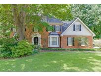 Charming two-story brick home with a manicured lawn and mature trees at 711 Belgrave Ln, Tucker, GA 30084