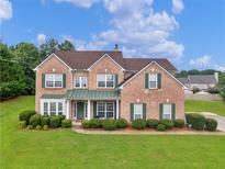 Charming two-story brick home with a well-manicured lawn and lush green landscaping at 1613 Brolington Ct, Conyers, GA 30013
