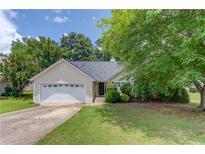 Charming single-story home featuring a two-car garage, well-maintained lawn, and beautiful landscaping at 949 Harbins Pass Dr, Dacula, GA 30019