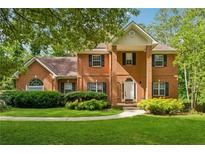 Charming two-story red brick home with a well-manicured lawn and lush green landscaping at 240 Old Plantation Way, Fayetteville, GA 30214