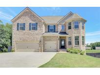 Traditional brick home with a three-car garage and well-manicured lawn under a blue sky at 932 Melville Dr, Stockbridge, GA 30281