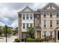 Charming brick townhome with a sunny yellow front door, inviting curb appeal, and flowering plants at 1995 Bryant Park Ln, Decatur, GA 30033