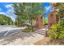 Charming street view featuring landscaped median, sidewalks, and brick entryway leading to lovely townhomes at 671 Brennan Dr, Decatur, GA 30033