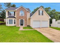 Charming two-story home featuring a two-car garage, stone accents, and a well-manicured lawn at 2428 Harmony Ridge Ct, Lithonia, GA 30058